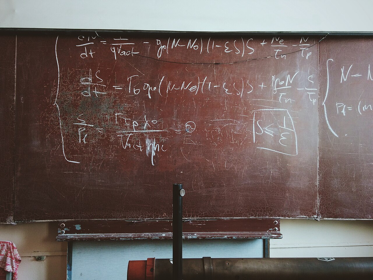 A worn chalkboard covered in dense mathematical formulas and equations
