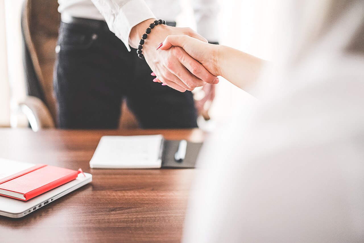 A close-up of a business handshake across a desk in an office