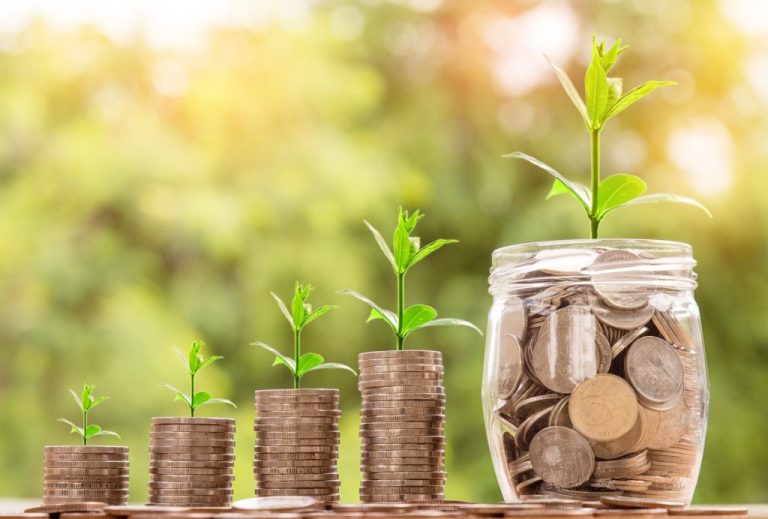 Stacks of coins growing taller with small plants sprouting from a jar of coins