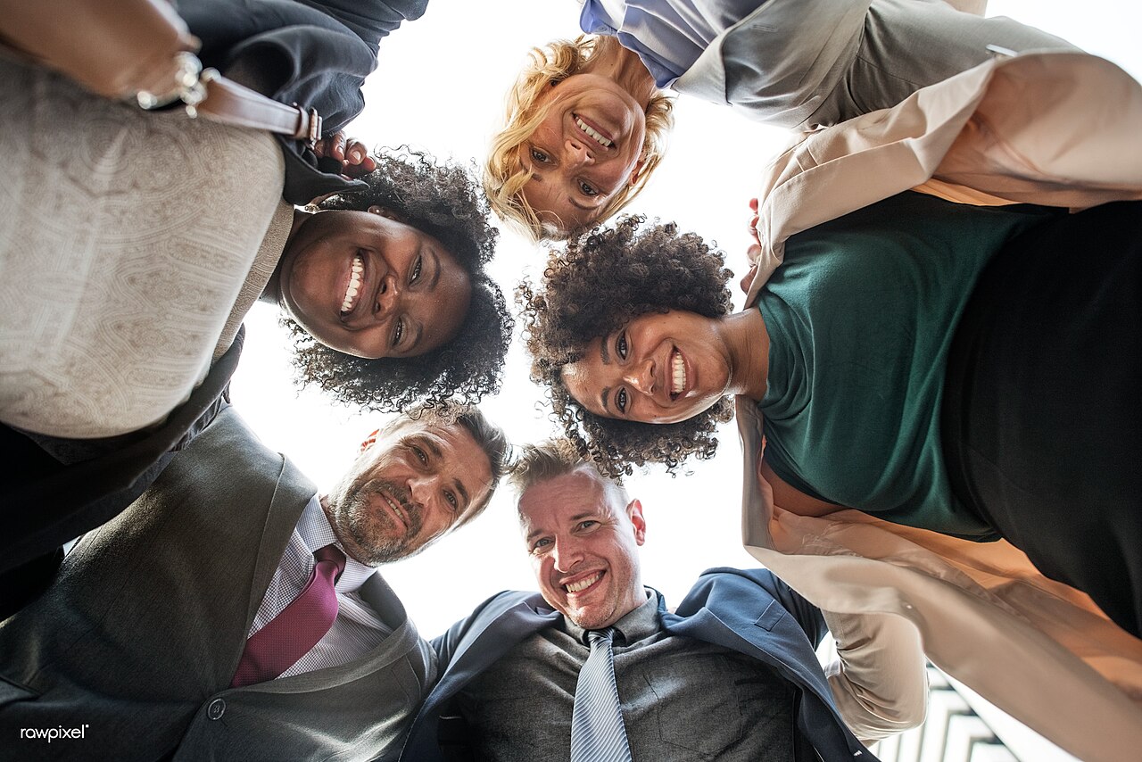 A diverse group of business people standing in a circle with heads together, representing a network