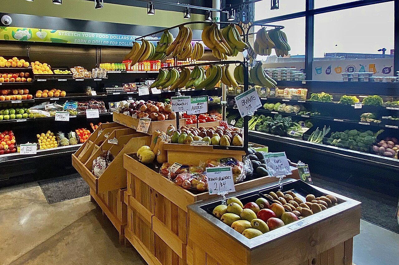 A well-stocked grocery store produce section with fresh fruits and vegetables on display