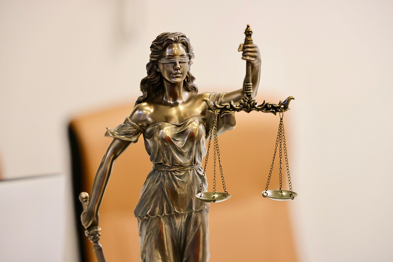 A close-up of a bronze Lady Justice statue, blindfolded and holding a set of balanced scales