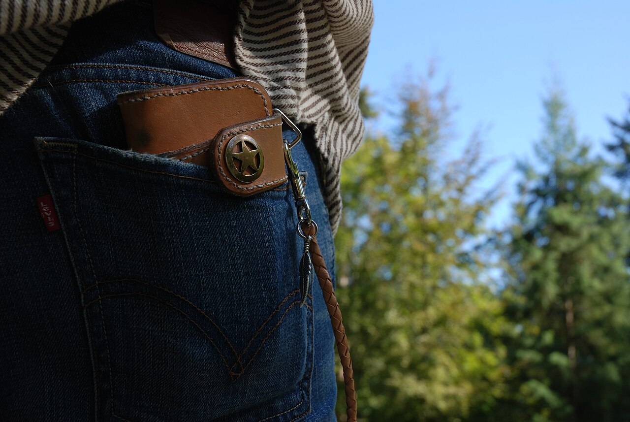 A brown leather wallet tucked into the back pocket of a pair of jeans