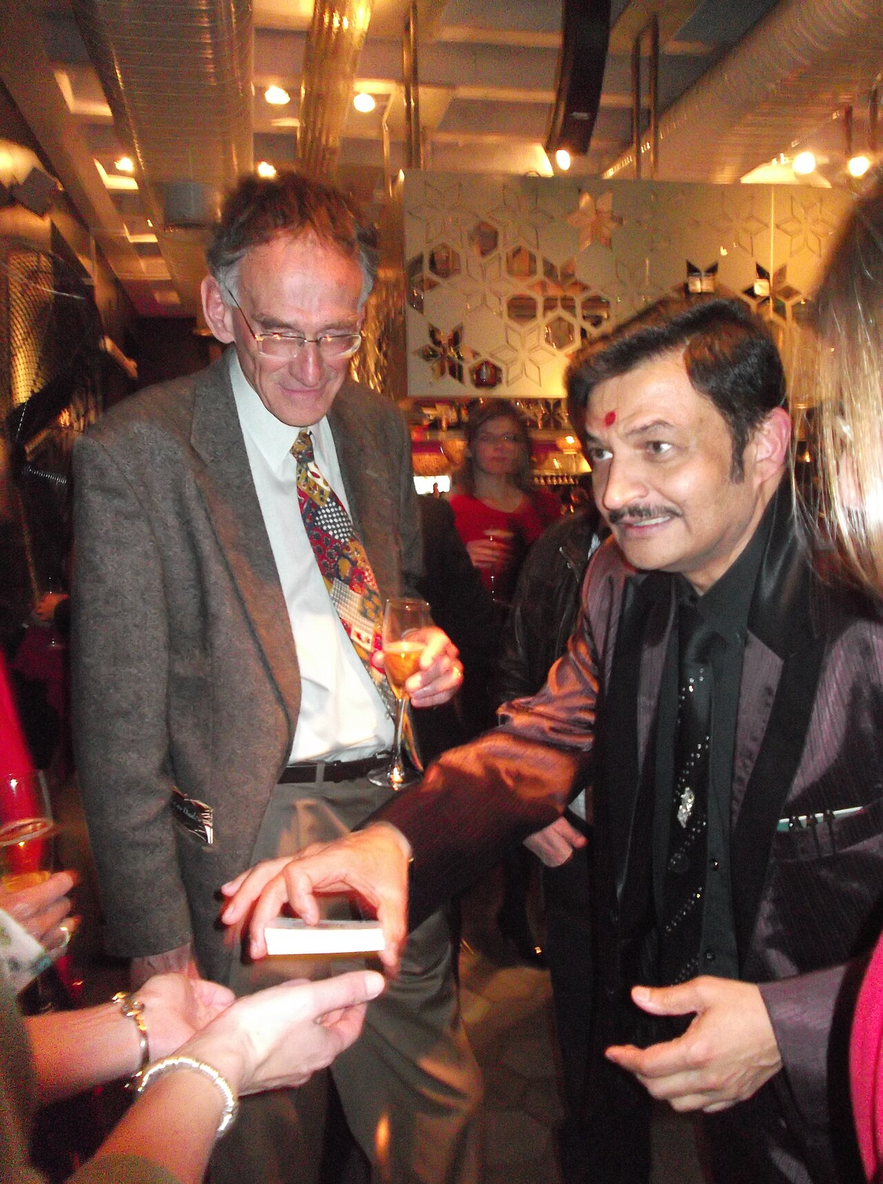 A magician performing a close-up card trick for an audience member, their attention fixed on his hands