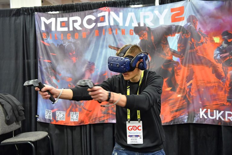 A young man wearing a VR headset and holding controllers while playing a game at a convention booth