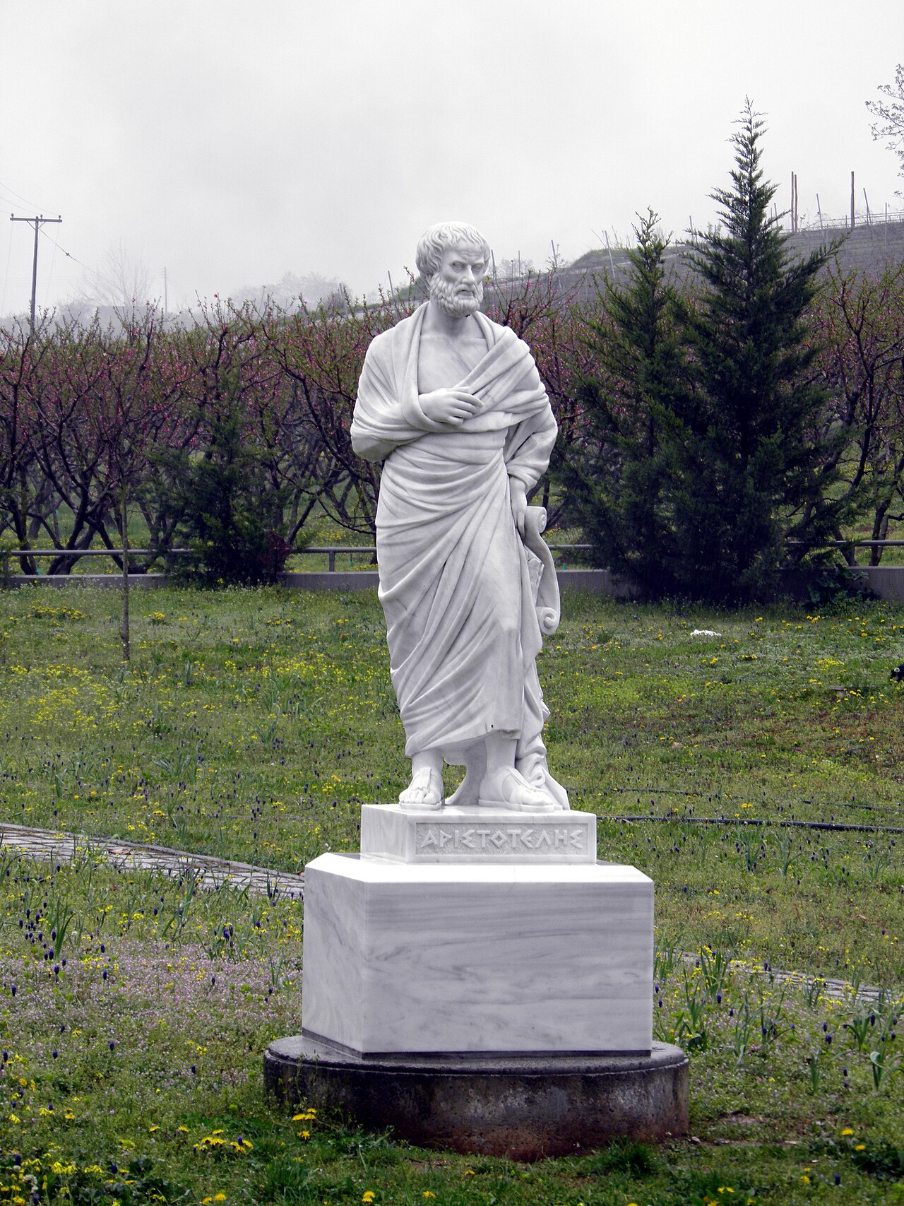 A marble statue of Aristotle standing in a garden near the site of his ancient school