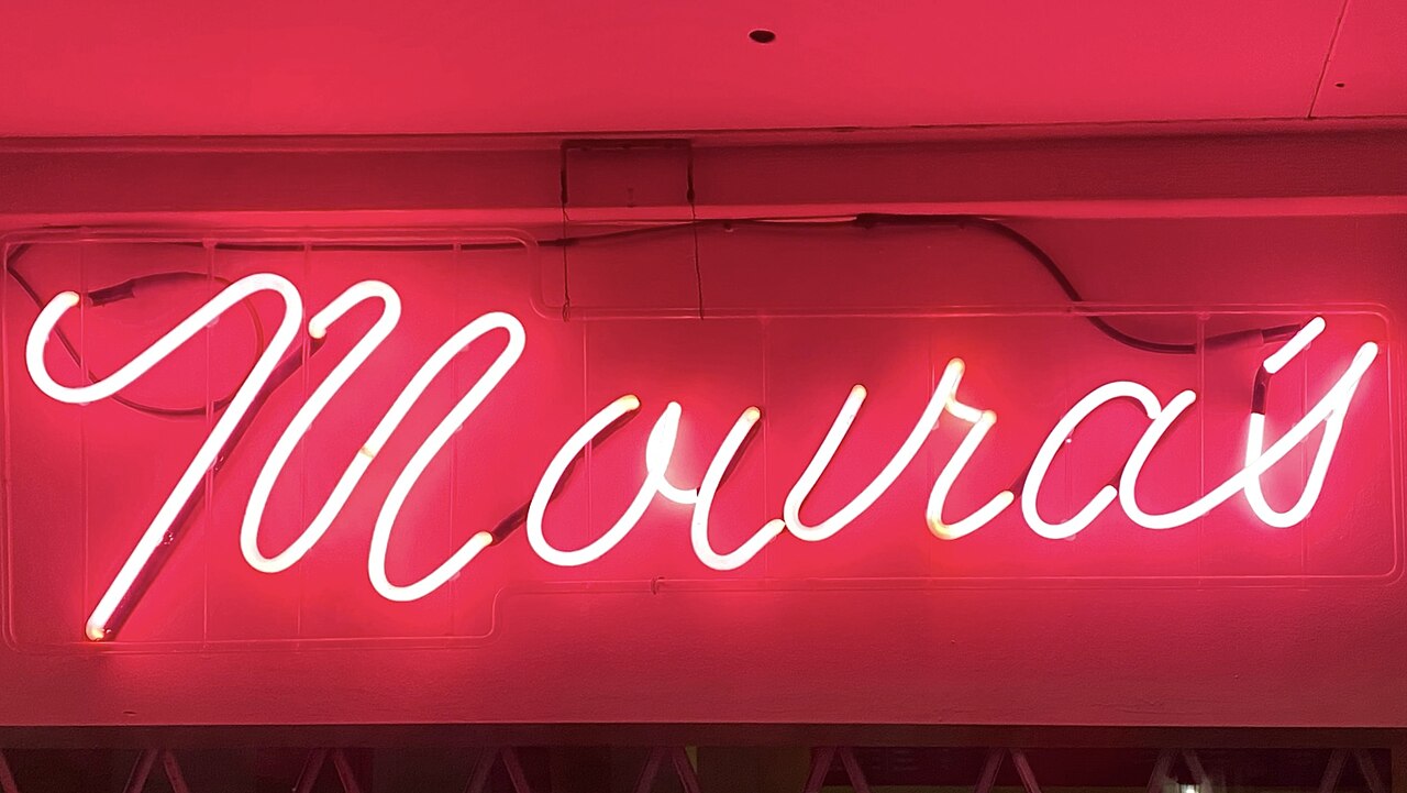 A glowing red neon shop sign spelling out a business name