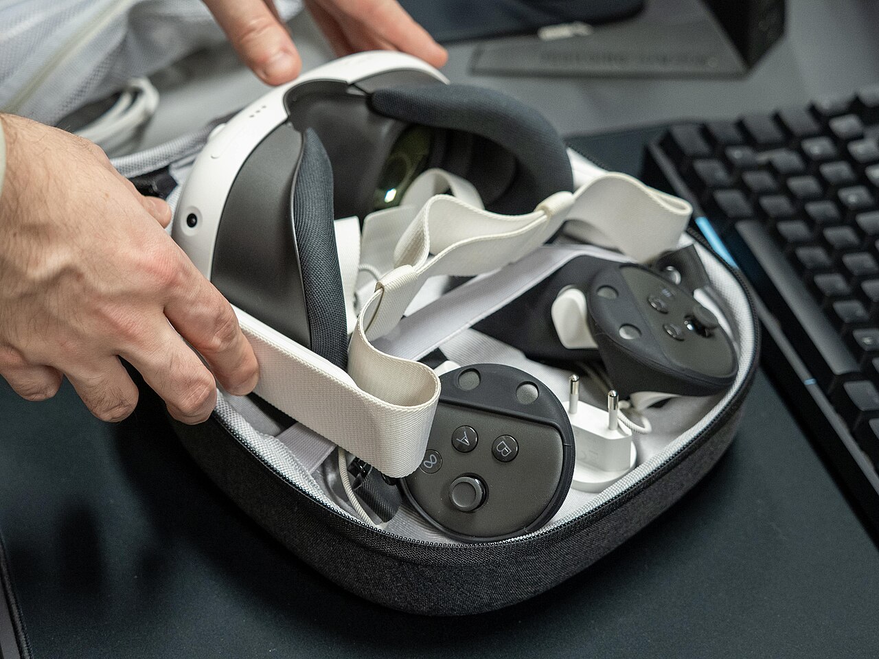 Hands packing an Oculus Quest VR headset and controllers into a carrying case
