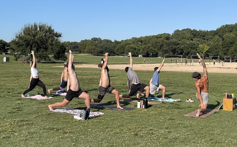 A group of people doing an outdoor yoga class in a park