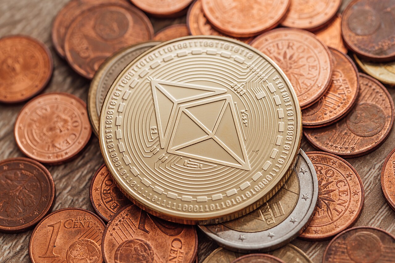 A close-up of a physical Ethereum coin resting among euro cent coins