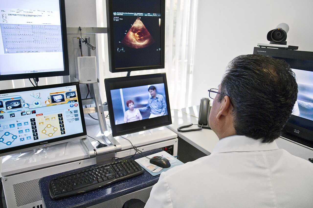 A physician reviewing medical monitors during a remote teleconsultation