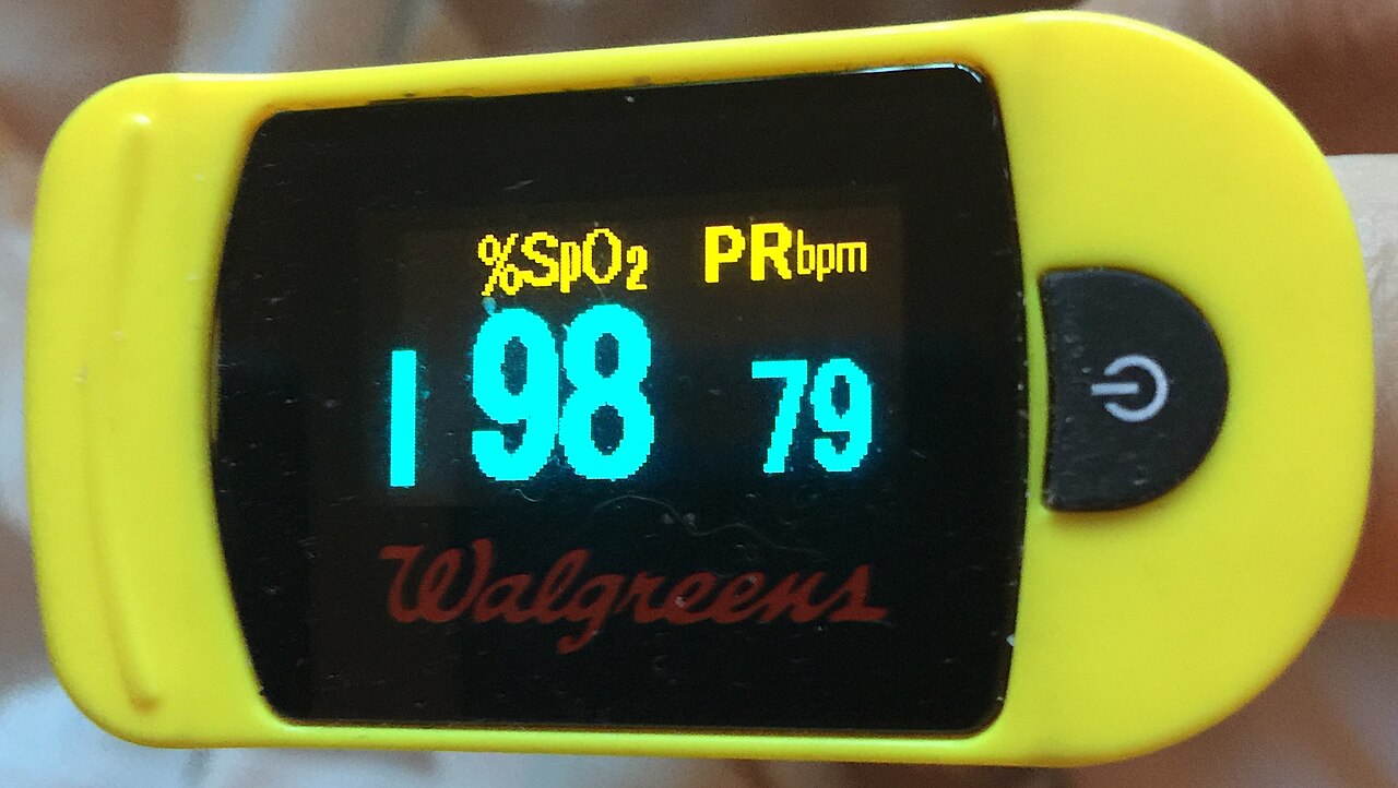 A pulse oximeter clipped on a finger showing oxygen saturation and heart rate readings