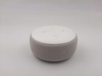 A smart speaker with a voice assistant sitting on a plain background