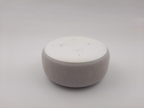 A smart speaker with a voice assistant sitting on a plain background