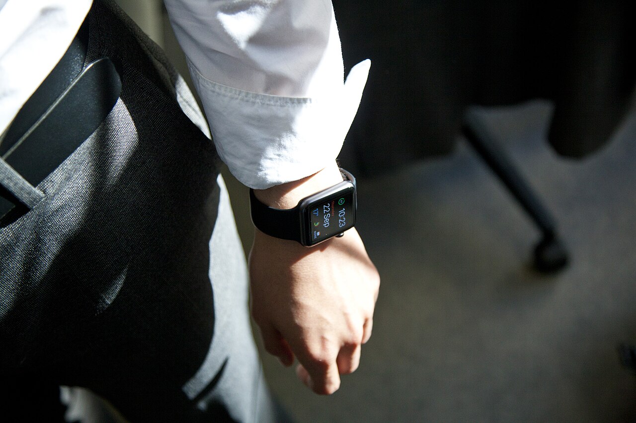 A close-up of a smartwatch on a businessman's wrist showing the time and date