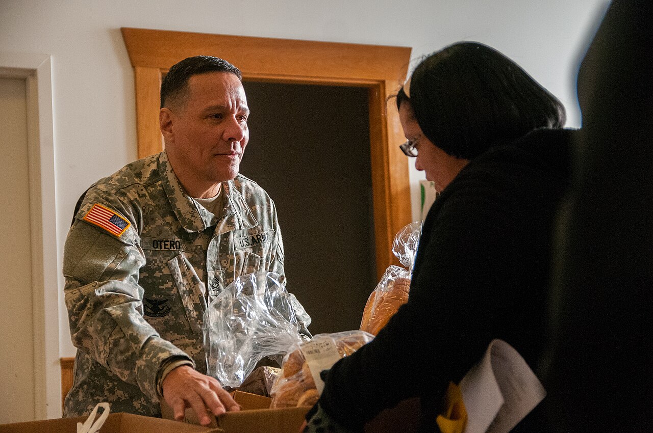 A soldier handing bread to a person in need at a community food distribution