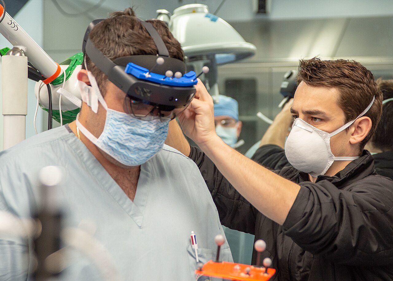 A surgeon in an operating room having a mixed-reality training headset adjusted before a procedure