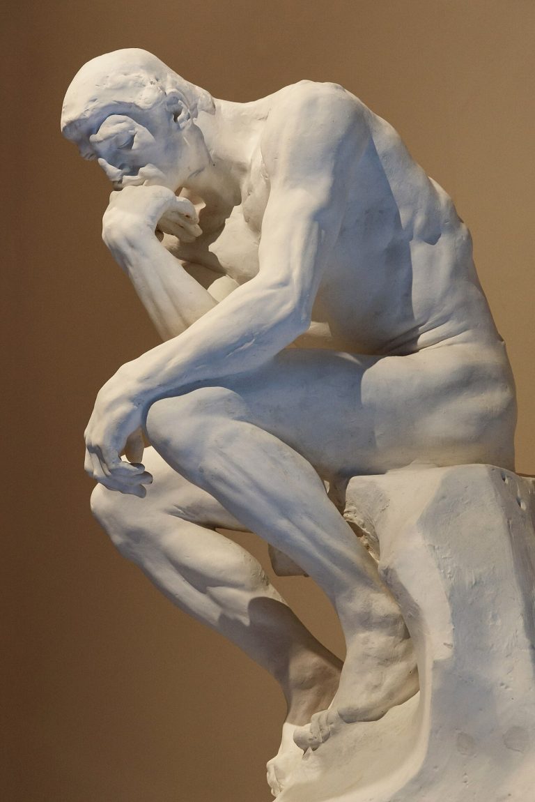 A close-up of Rodin's sculpture The Thinker, showing a figure deep in contemplation