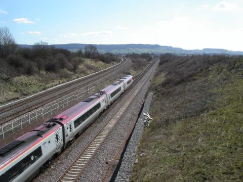 A train traveling along tracks that fork into two diverging paths in the countryside
