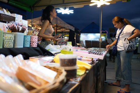 A vendor showing cosmetics products to a customer at a market stall