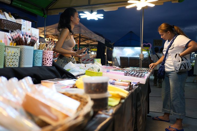 A vendor showing cosmetics products to a customer at a market stall