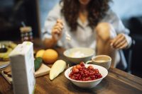 A woman enjoying a healthy breakfast with fresh fruit, yogurt, and coffee at home